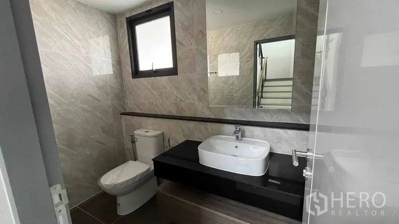 Detached House for sale in Bang Phli, Samut Prakan - Guest bathroom with vanity, large mirror and window for natural light.