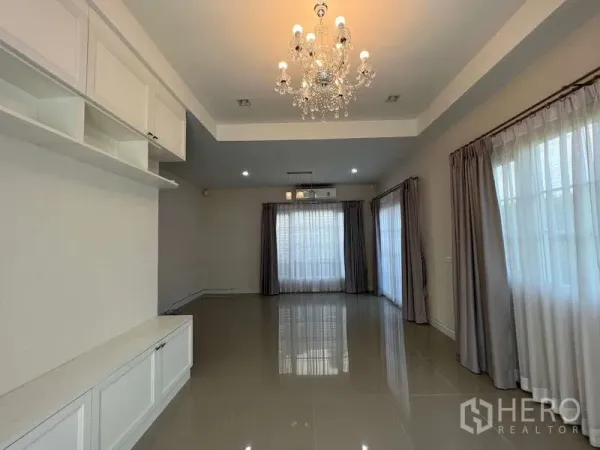 Detached House for rent or sale in Khan Na Yao, Bangkok - Bright living room with chandelier, glossy tile floors and full-height curtains.