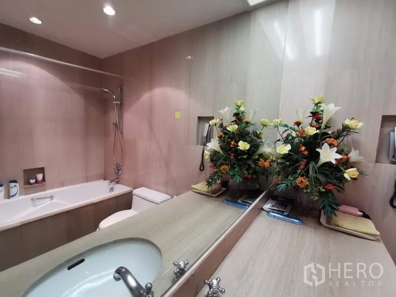 Condominium for rent in Pathum Wan, Bangkok - Modern bathroom with long vanity, bathtub with shower and large mirror.