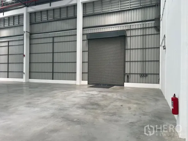 工厂 出租在Bang Pakong, Chachoengsao - 明亮的厂房内部，抛光混凝土地面、挑高空间与大型卷闸装卸门。