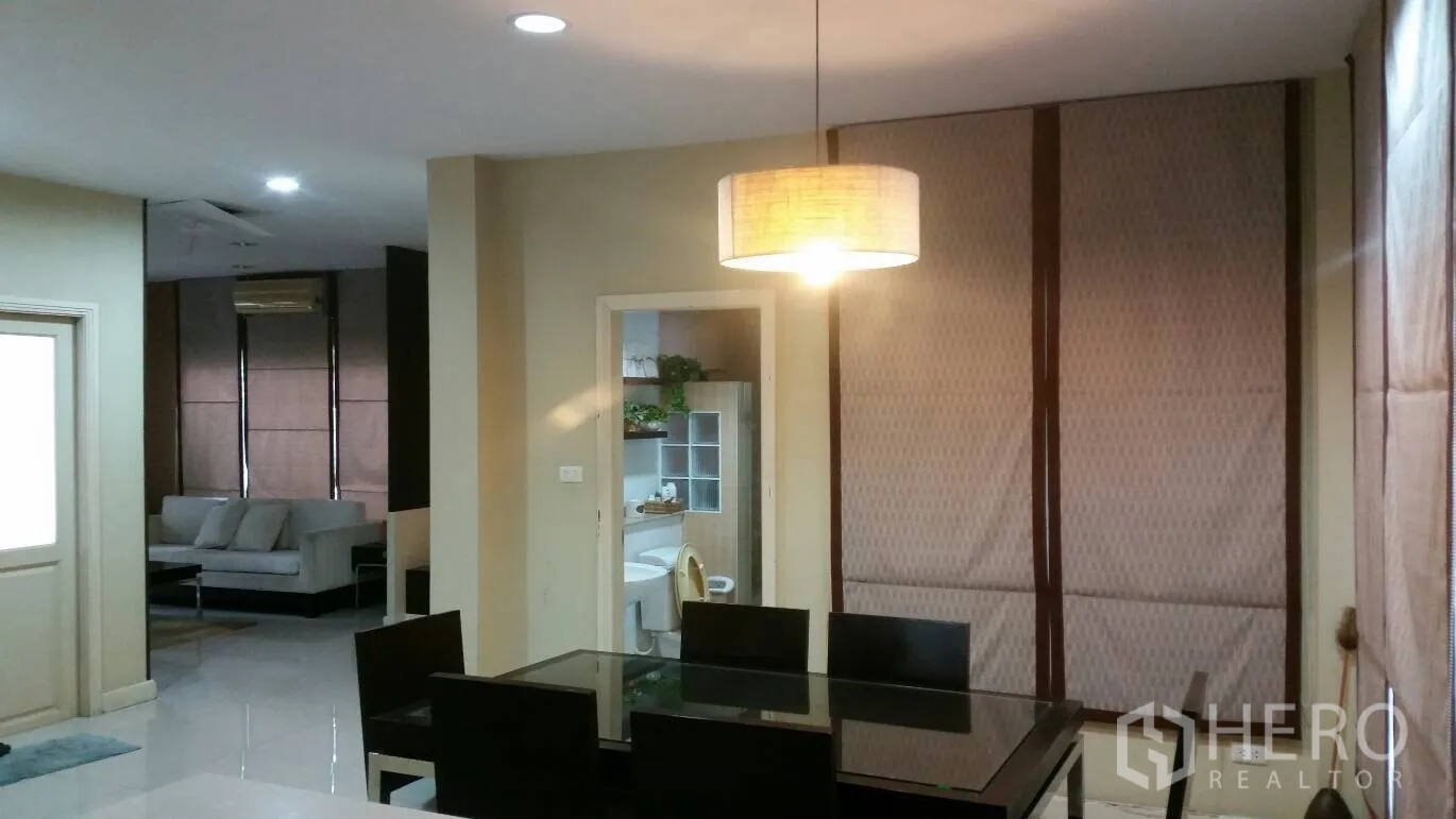 Detached House for rent in Lat Krabang, Bangkok - Open‑plan dining area with pendant light, glass table, and a view to the lounge and bathroom.