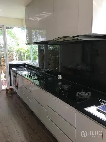 联排别墅 出售在Huai Khwang, Bangkok - 现代一字型厨房，黑色花岗岩台面，燃气灶与花园景窗。