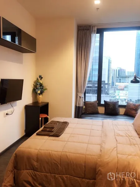 คอนโด ให้เช่าในWatthana, Bangkok - มุมห้องนอนมีทีวีติดผนัง โต๊ะทำงานเล็ก และม้านั่งริมหน้าต่างมองเห็นตึกสูง