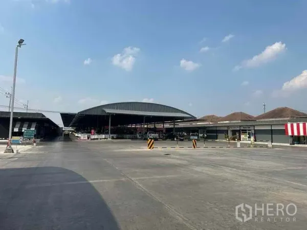 Retail Space for rent in Pathum Thani - Wide concrete forecourt with covered market pavilions and easy vehicle access under a clear sky.