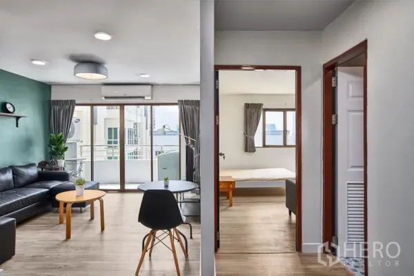 Condominium for rent in Watthana, Bangkok - Open-plan lounge with floor-to-ceiling windows and doorway to a bedroom in a Bangkok condo.