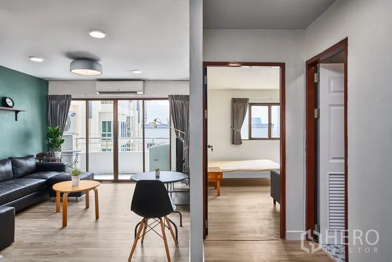 Condominium for rent in Watthana, Bangkok - Open-plan lounge with floor-to-ceiling windows and doorway to a bedroom in a Bangkok condo.