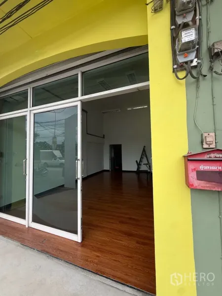 Shophouse for rent in Pak Kret, Nonthaburi - Glass-front shophouse entrance with sliding doors and wood-look flooring.