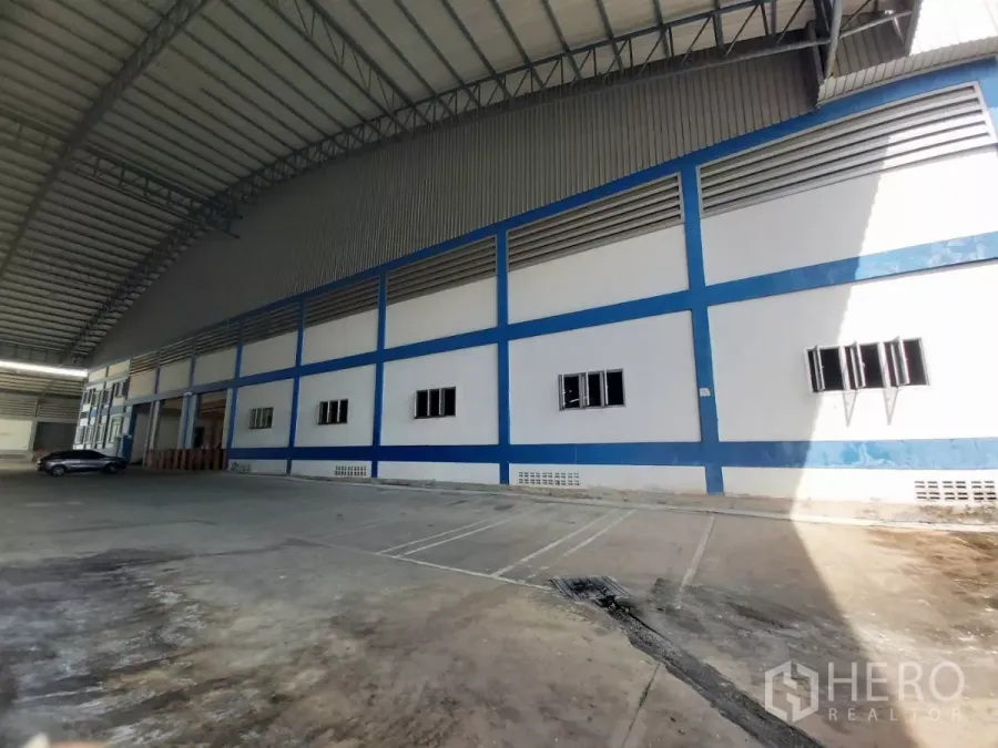 Warehouse for rent in Bang Bo, Samut Prakan - Covered loading yard beside a blue and white warehouse facade with high roof.