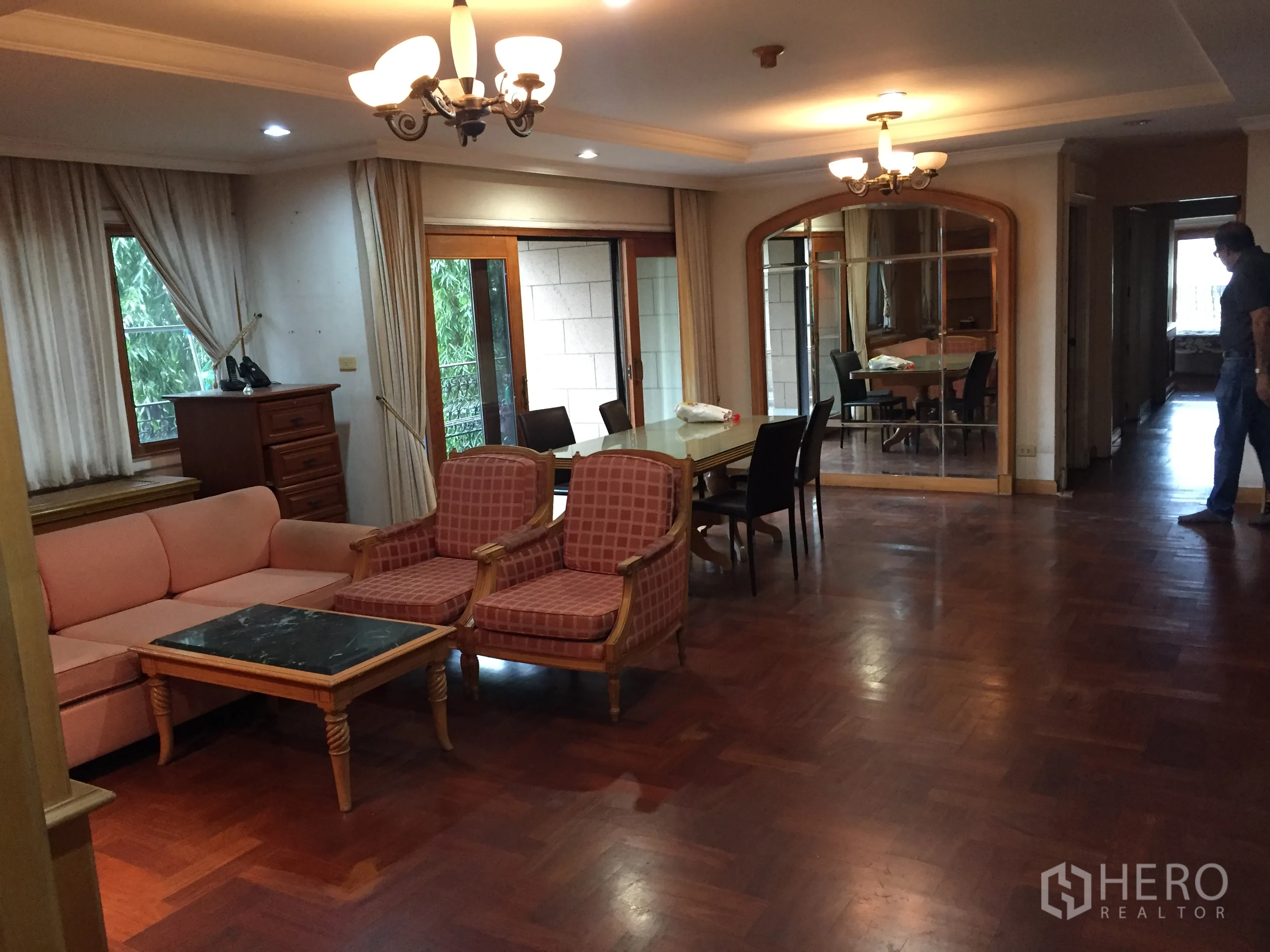Condominium for rent in Khlong Toei, Bangkok - Spacious living and dining area with parquet floors, chandeliers and glass doors to a balcony.