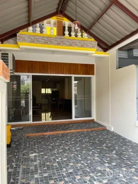 Townhouse for rent in Bang Na, Bangkok - Covered carport with tiled floor and sliding glass entry at a Bang Na townhouse.