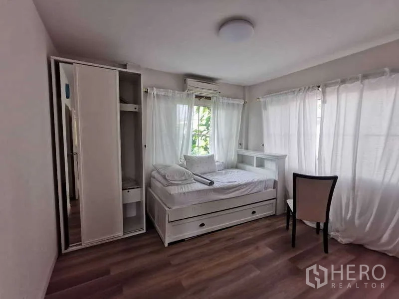Detached House for rent - Light-filled bedroom with a single bed with trundle, wardrobe, chair, and sheer curtains around large windows.