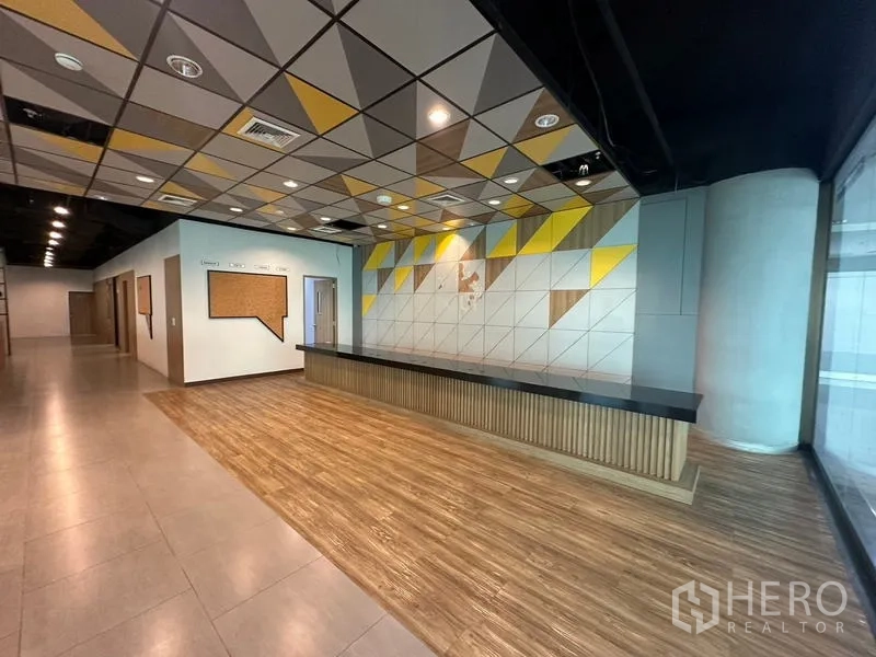 สำนักงาน ให้เช่าในRatchathewi, Bangkok - เคาน์เตอร์ประชาสัมพันธ์ ผนังไฮไลต์ลายสามเหลี่ยมเหลือง‑เทา และกระจกเต็มบาน