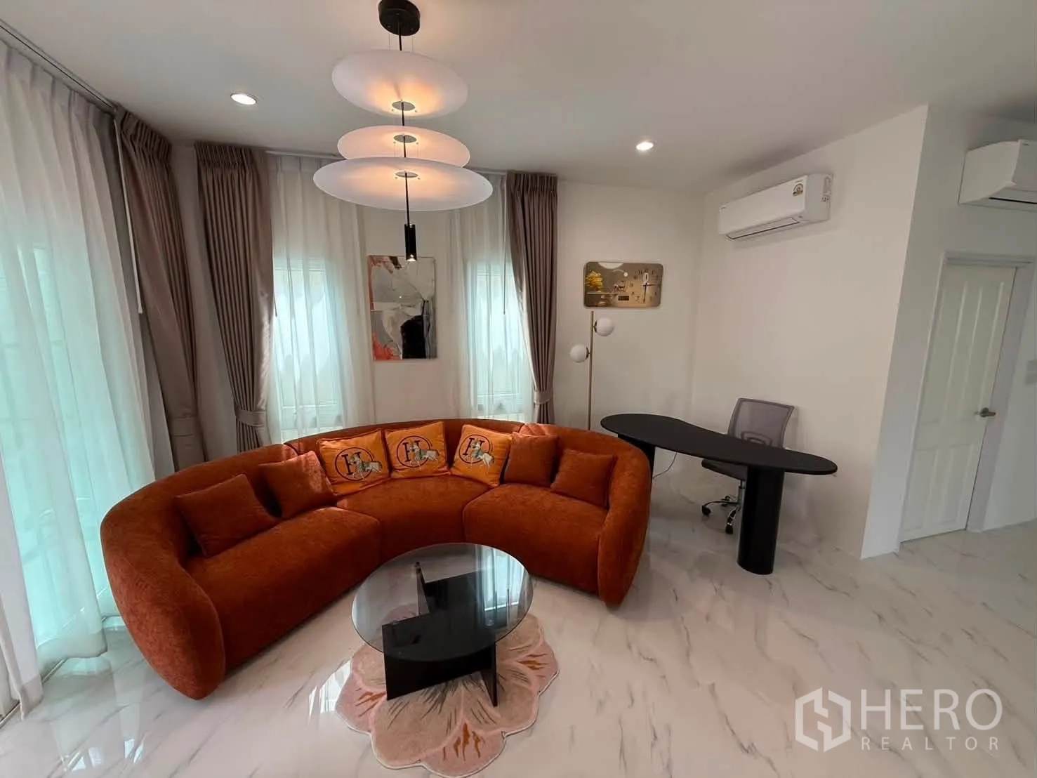 บ้านเดี่ยว for rent in Bang Phli, Samut Prakan - มุมนั่งเล่นโซฟาทรงโค้งสีส้ม โต๊ะกระจก และโต๊ะทำงาน.