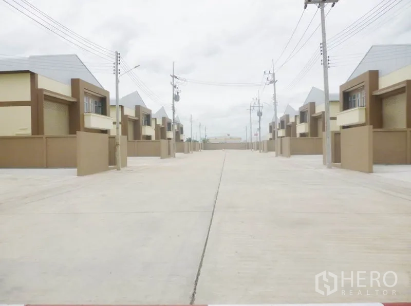 Factory for sale in Pathum Thani - Wide concrete road within the industrial compound with power lines and multiple factory units.