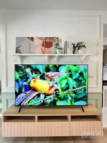 Townhouse for rent in Bang Phli, Samut Prakan - Living room media wall with floating shelf and a large TV on a wooden cabinet.