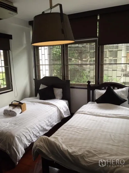 Detached House for rent in Watthana, Bangkok - Bright bedroom with twin single beds, large pendant light and corner windows with garden outlook.