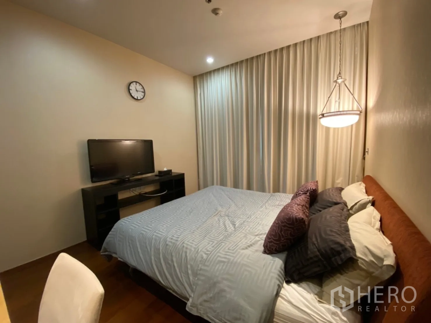 公寓 出租在Watthana, Bangkok - 主卧设电视柜、挂钟与薄纱窗帘。