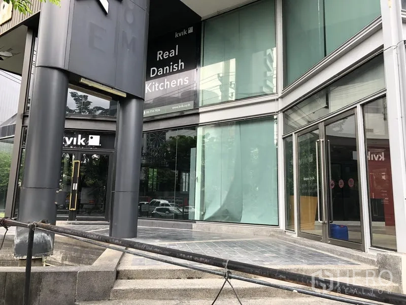 零售空间 出租在Watthana, Bangkok - 转角入口的玻璃展厅，双扇玻璃门与宽台阶，临街展示窗。