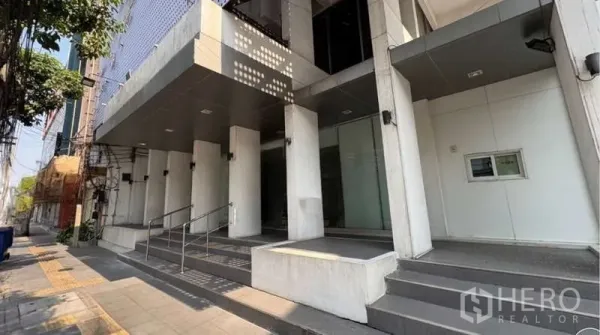 Standalone for rent in Khlong Toei, Bangkok - Modern standalone building entrance with glass facade, steps and ramp in Khlong Toei.