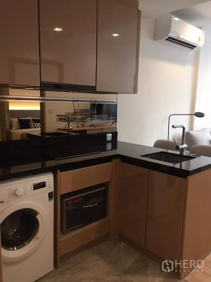 公寓 出租在Watthana, Bangkok - 内置厨房，黑色石材台面，带洗衣机与亮面柜体。