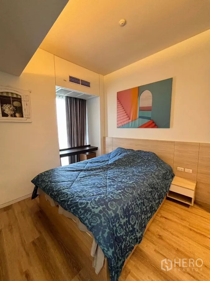 Condominium for rent or sale in Phaya Thai, Bangkok - Second bedroom with wood flooring, window, and colorful wall art above the bed.