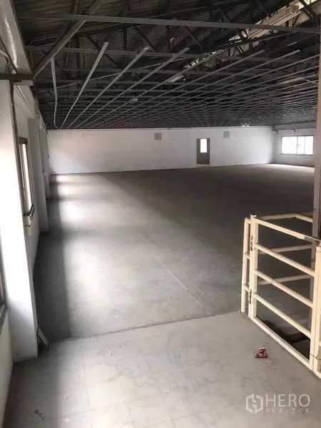 Factory for rent in Bang Bua Thong, Nonthaburi - Wide open floor beneath a metal roof structure with windows along the wall.