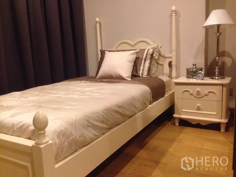 Condominium for rent in Khlong Toei, Bangkok - Second bedroom with single bed, white classic furniture and bedside table lamp.