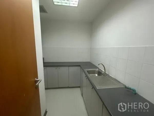办公空间 出租在Phaya Thai, Bangkok - 紧凑茶水间，配备水槽、灰色台面与白色瓷砖墙面。