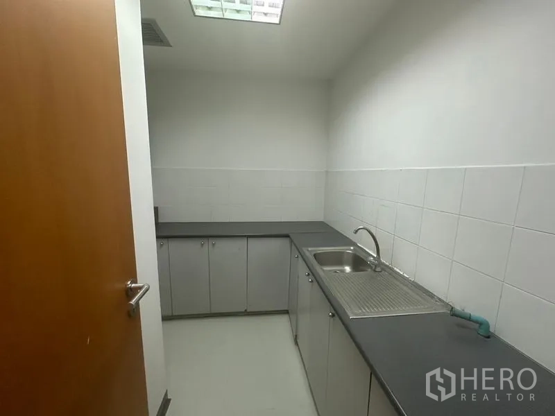 办公空间 出租在Phaya Thai, Bangkok - 紧凑茶水间，配备水槽、灰色台面与白色瓷砖墙面。