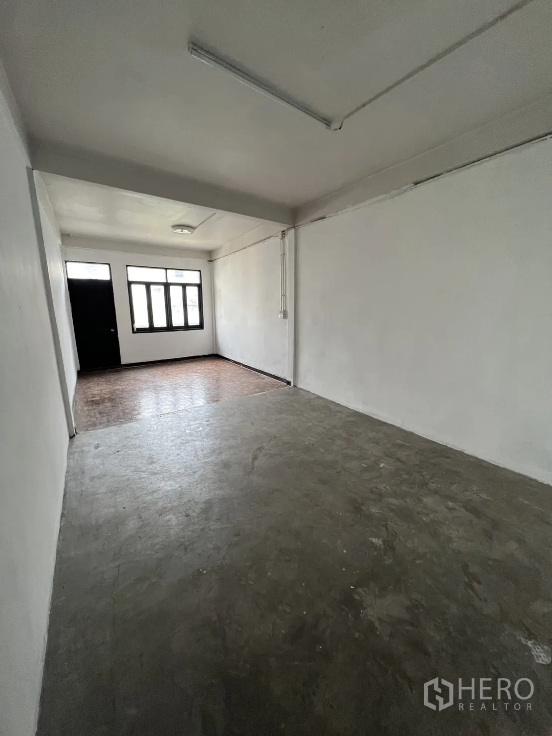 Shophouse for rent in Watthana, Bangkok - Bright room with concrete floor leading to a windowed area.