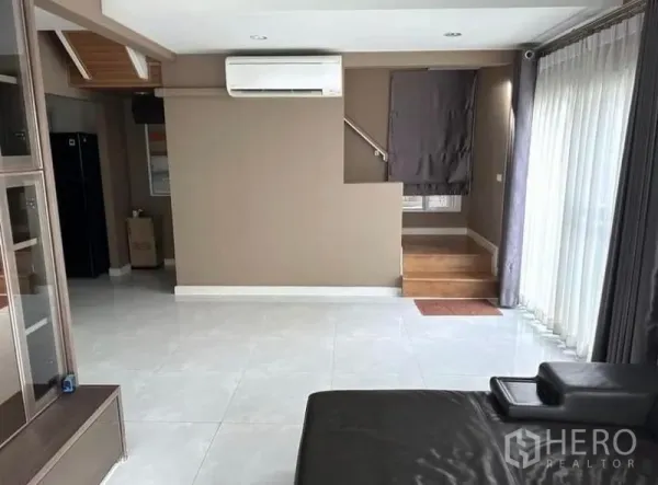 独立式住宅 出租在Suan Luang, Bangkok - 通透起居区，亮面地砖、楼梯与大幅推拉玻璃门。