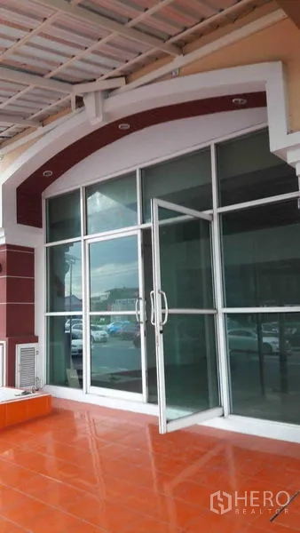 办公空间 出租在Bueng Kum, Bangkok - 整面玻璃门窗的建筑外立面，带遮棚和橙色地砖平台。