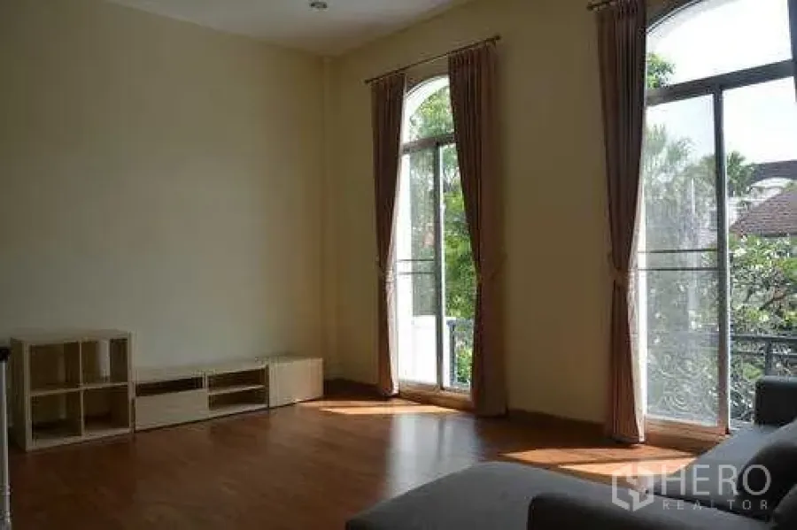 带办公室的家 出租在Wang Thonglang, Bangkok - 采光充足的客厅，拱形落地窗与阳台栏杆，可见园景，位于王通朗区。
