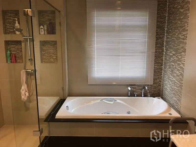Detached House for rent or sale in Saphan Sung, Bangkok - Modern bathroom with glass shower enclosure and a bathtub beneath a window.
