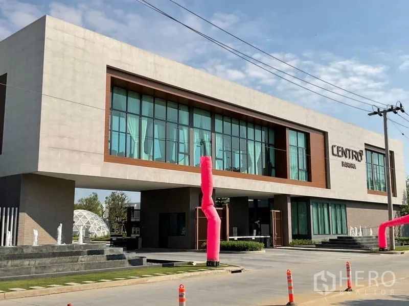 Detached House for rent - Contemporary community clubhouse at Centro Bangna with large glass facade and water features.