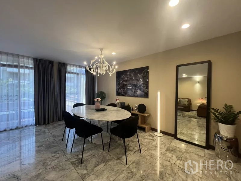 Townhouse for rent or sale in Suan Luang, Bangkok - Dining zone with round marble table, chandelier and wall art.