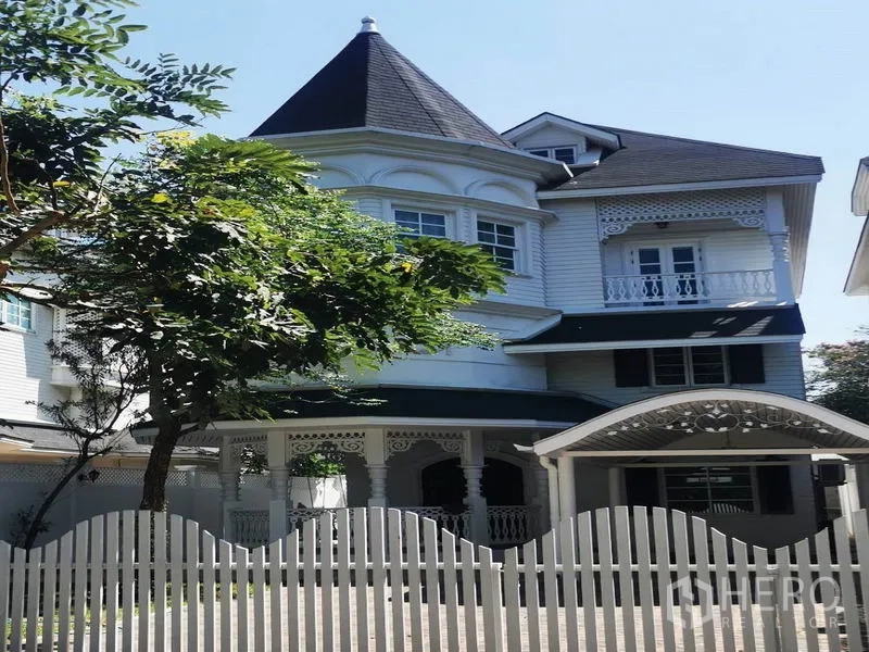 Detached House for rent in Mueang Samut Prakan, Samut Prakan - Three-storey white detached house with turret roof, balconies and a white picket fence.