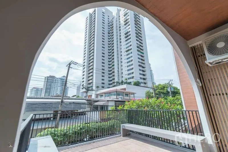ทาวน์เฮาส์ for rent in Watthana, Bangkok - ระเบียงกึ่งเอาต์ดอร์ซุ้มโค้ง มองเห็นตึกสูงของเมืองผ่านราวเหล็กสีดำ