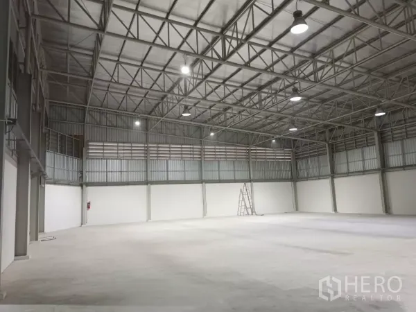 Warehouse for rent in Khlong Sam Wa, Bangkok - Spacious warehouse interior with high steel trusses, bright LED lights, and smooth concrete floor.