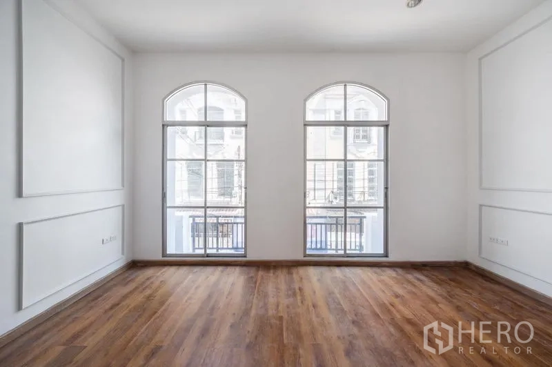 Townhouse for sale - Front bedroom with three arched windows and balcony railings.