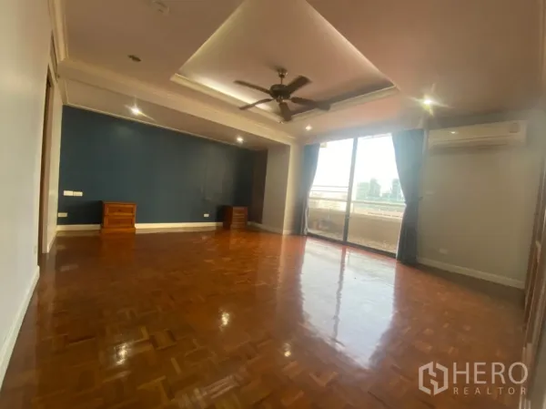 Condominium for rent or sale in Watthana, Bangkok - Large master bedroom or family room with ceiling fan, wood floors and balcony access.