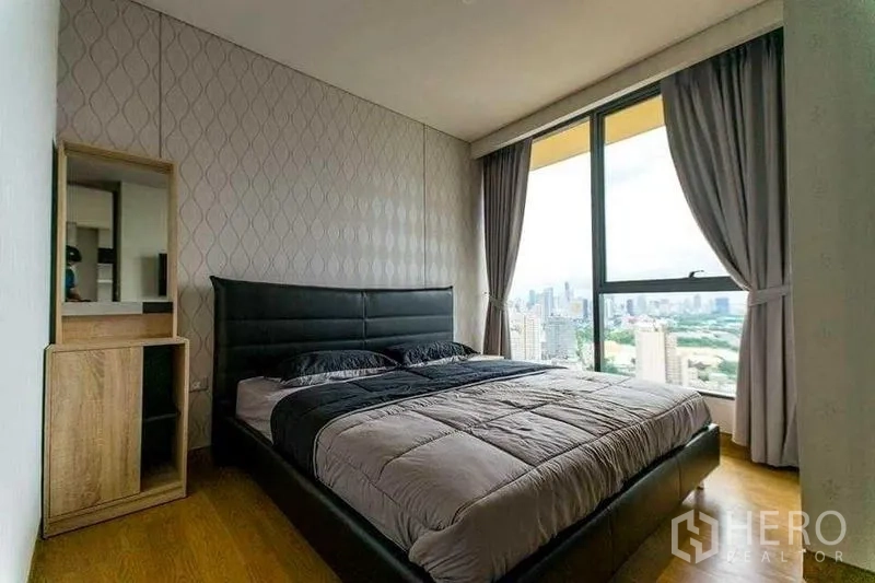 Condominium for rent in Khlong Toei, Bangkok - Cozy bedroom with a large window, curtains and panoramic city outlook.