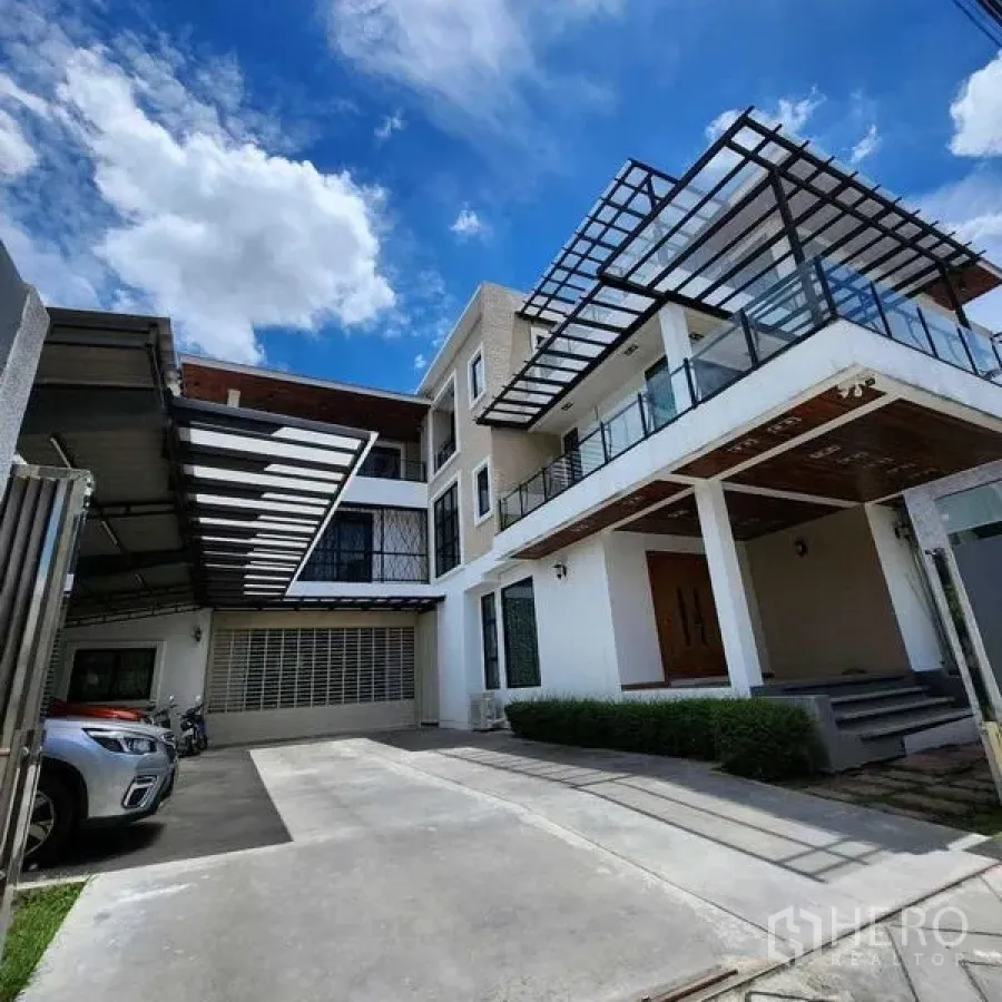 独立式住宅 出售在Phra Khanong, Bangkok - 宽阔车道与现代立面，玻璃栏杆阳台和金属雨棚