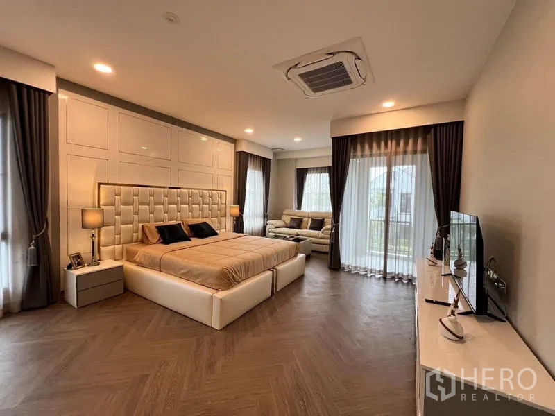 Detached House for rent or sale in Saphan Sung, Bangkok - Large master bedroom with balcony doors, seating corner and recessed lighting.