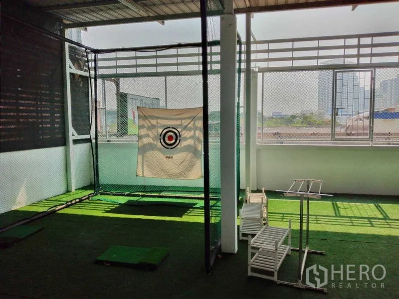 Shophouse for rent in Watthana, Bangkok - Covered rooftop terrace with netted practice area and city views in the background.