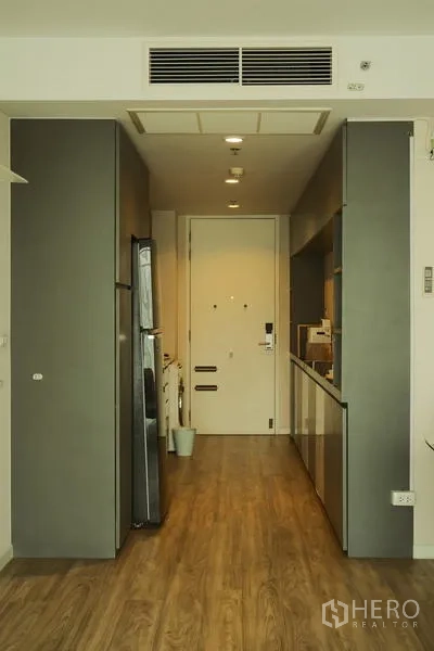 Condominium for rent in Bang Rak, Bangkok - Entry hallway with open kitchenette, wood flooring and full-height cabinets.