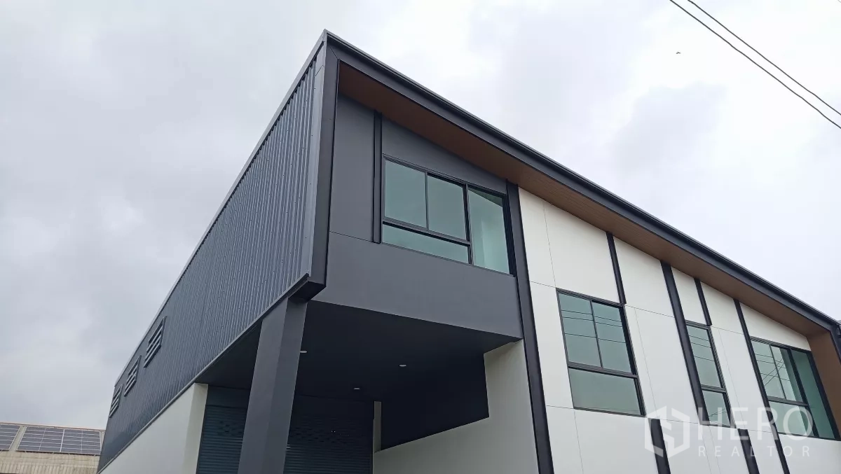 Warehouse for rent or sale in Lam Luk Ka, Pathum Thani - Close-up of the corner showing metal cladding, canopy, and upper office windows.