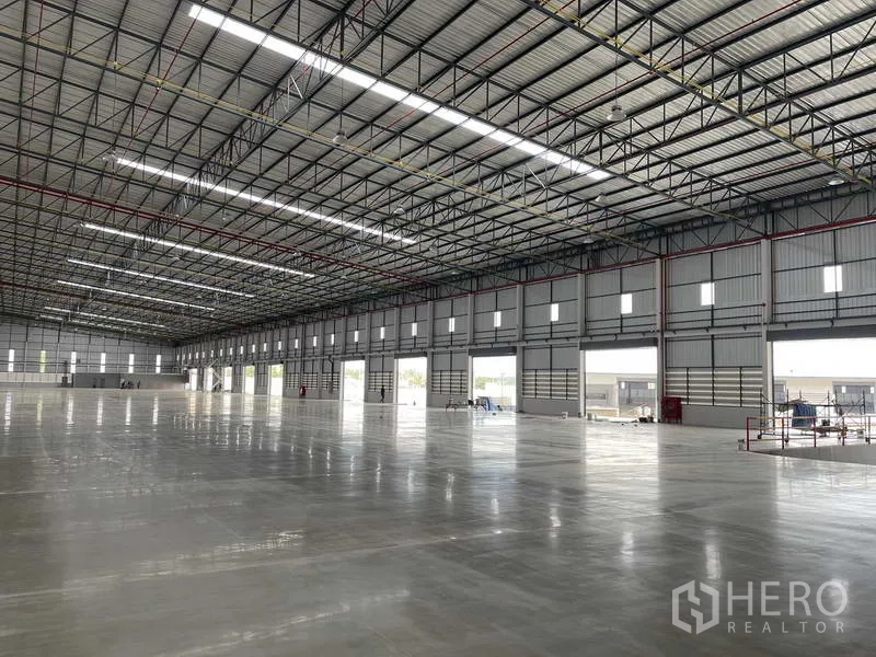 工厂 出租在Si Racha, Chon Buri - 侧墙排布多扇卷帘装卸门与采光带，便于装卸。