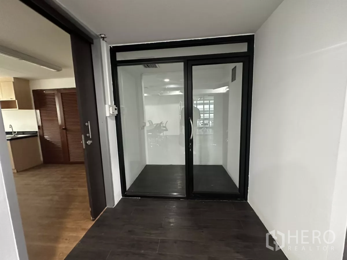 Office Space for rent in Watthana, Bangkok - Entry foyer with black-framed glass double doors opening to the main workspace.