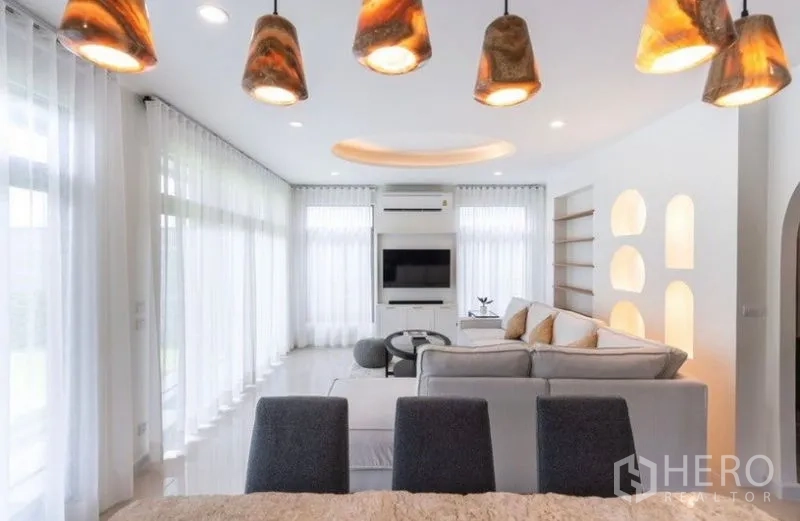 Detached House for rent or sale in Saphan Sung, Bangkok - Open-plan dining and living area with pendant lights and floor-to-ceiling windows.